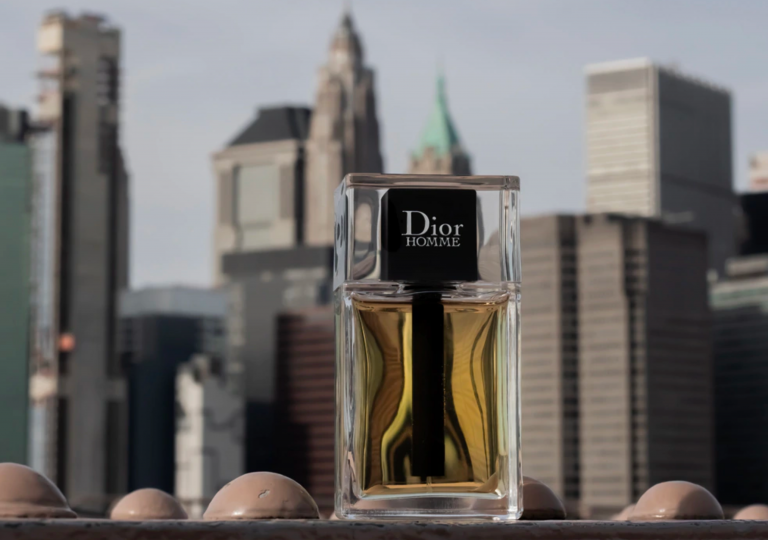 The Dior Homme bottle in close-up on a steel beam of the Brooklyn Bridge, with the New York skyline in the background